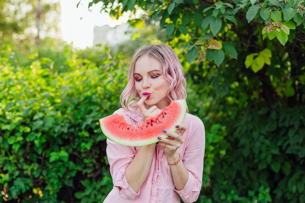 Beautiful young woman with pink hair enjoying watermelon — Stock Photo, Image