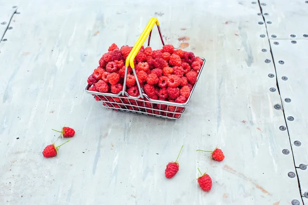 Mini shopping basket full of fresh red ripe raspberry on vintage background