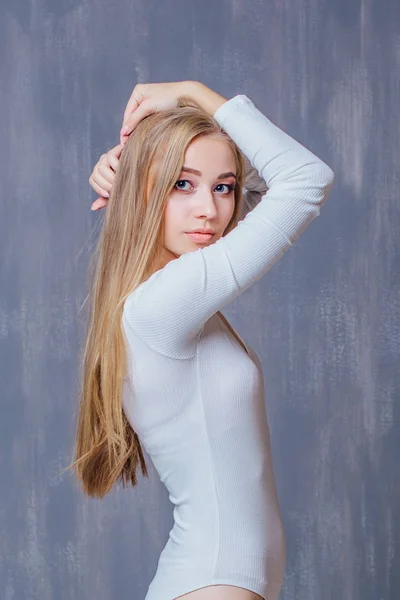 Bella giovane donna con lunghi capelli biondi in body bianco . — Foto Stock