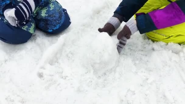 Kids playing with melting snow, making shapes of snow — Stock Video