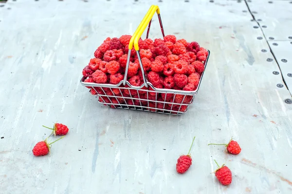 Mini shopping basket full of fresh red ripe raspberry on vintage background