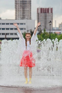 Sarı çizmeli genç, ıslak güzel kız çeşmenin içinde duruyor..