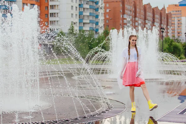 Gadis cantik basah muda dengan dua kepang sepatu kuning berdiri di dekat air mancur . — Stok Foto