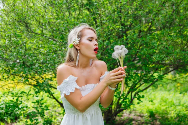 Schöne blonde Frau bläst auf weißen Pusteblume — Stockfoto