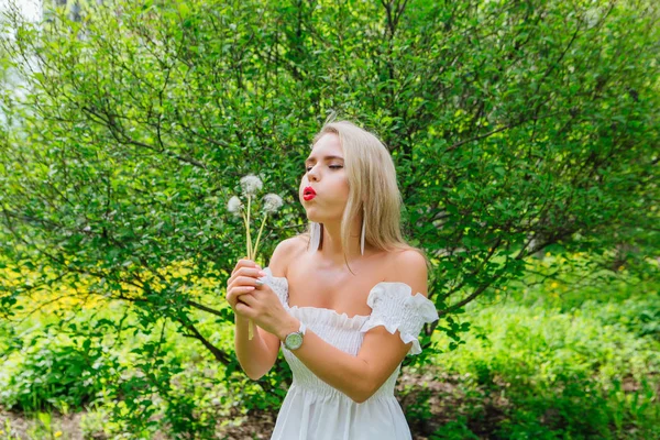 Mooie blonde vrouw waait op witte Blow Ball — Stockfoto