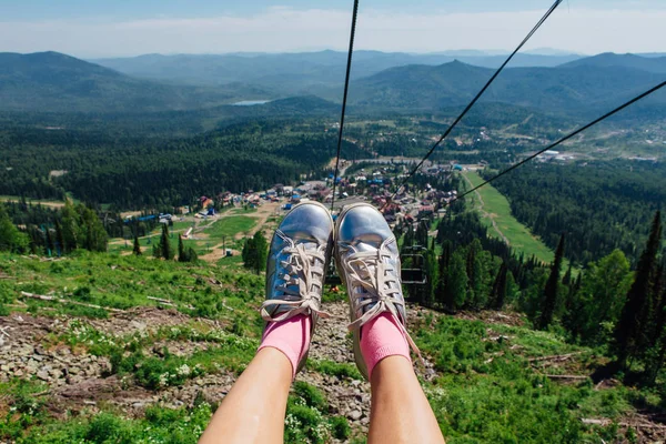 Silver shoes on feet during travel on mountain ski lift at summer time