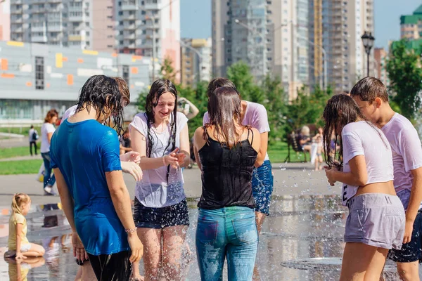 Novokuznetsk, Kemerovo Region, Russia - August 04, 2018: Happy teenagers splashing in a water of a city fountain and enjoying the cool streams of water in a hot day. — Stock Photo, Image