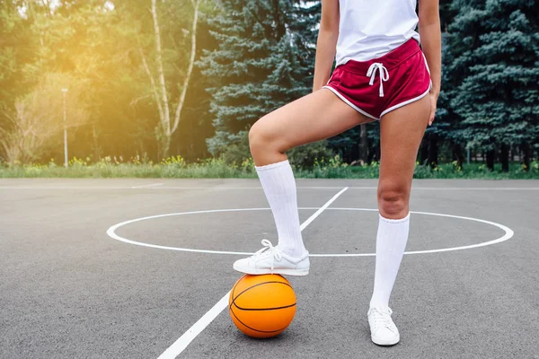 Menutup kaki wonan dengan sepatu putih dan kaus kaki panjang, dengan bola di lapangan basket . — Stok Foto