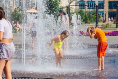 Novokuznetsk, Kemerovo Region, Rusya-04 Ağustos 2018: mutlu gençler bir şehir Çeşmesi suda sıçramak ve sıcak bir günde su serin akışları zevk.