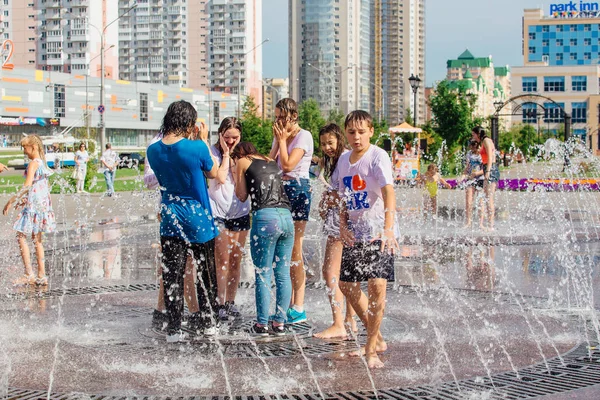 Novokuznetsk, Regione di Kemerovo, Russia - 04 agosto 2018: Adolescenti felici che schizzano in un'acqua di una fontana cittadina e si godono i freschi corsi d'acqua in una giornata calda . — Foto Stock