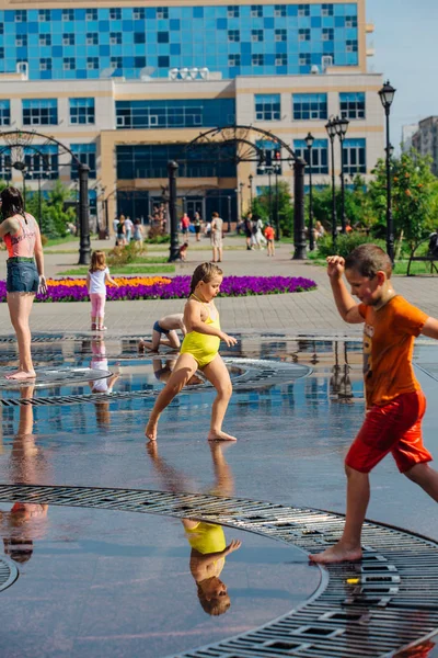 俄罗斯克麦罗沃地区新库兹涅茨克-2018年8月4日: 快乐的青少年在城市喷泉的水中飞溅, 在炎热的天气里享受凉爽的水流. — 图库照片