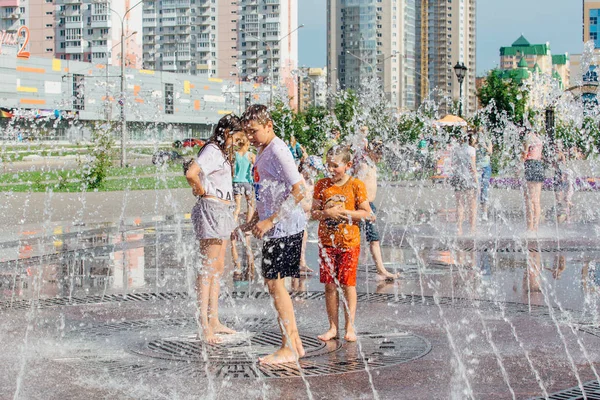 Novokuznetsk, Kemerovo Region, Russia - August 04, 2018: Happy teenagers splashing in a water of a city fountain and enjoying the cool streams of water in a hot day. — Stock Photo, Image