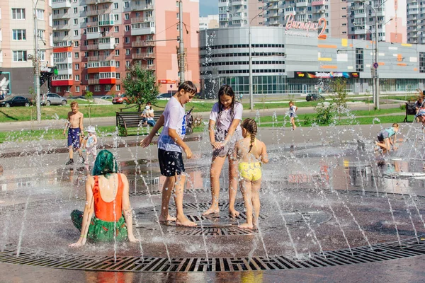 Novokuznetsk, Regione di Kemerovo, Russia - 04 agosto 2018: Adolescenti felici che schizzano in un'acqua di una fontana cittadina e si godono i freschi corsi d'acqua in una giornata calda . — Foto Stock