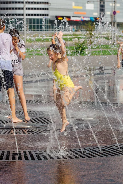 Novokuznetsk, Kemerovo Region, Russia - August 04, 2018: Happy teenagers splashing in a water of a city fountain and enjoying the cool streams of water in a hot day. — Stock Photo, Image
