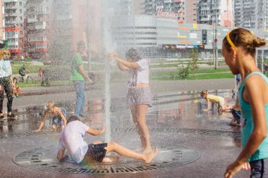 Novokuznetsk, Kemerovo Region, Rusya-04 Ağustos 2018: mutlu gençler bir şehir Çeşmesi suda sıçramak ve sıcak bir günde su serin akışları zevk.