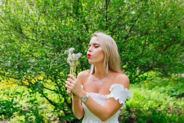 Schöne blonde Frau bläst auf weißen Pusteblume — Stockfoto