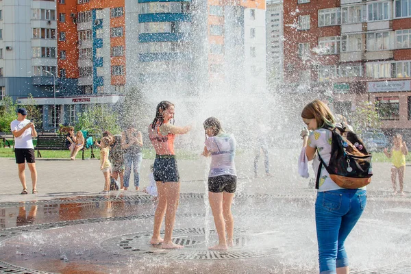 Novokuznetsk, Región de Kemerovo, Rusia - 04 de agosto de 2018: Adolescentes felices salpicando en el agua de una fuente de la ciudad y disfrutando de los frescos arroyos de agua en un día caluroso . — Foto de Stock