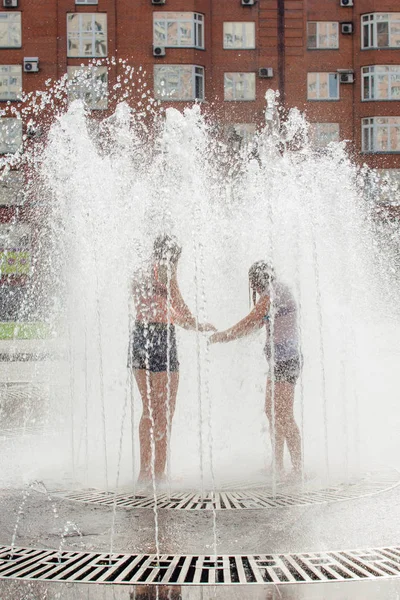 Novokuznetsk, Kemerovo Region, Russia - August 04, 2018: Happy teenagers splashing in a water of a city fountain and enjoying the cool streams of water in a hot day. — Stock Photo, Image