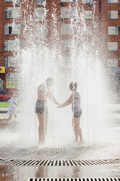 Novokuznetsk, Kemerovo Region, Russia - August 04, 2018: Happy teenagers splashing in a water of a city fountain and enjoying the cool streams of water in a hot day. — Stock Photo, Image
