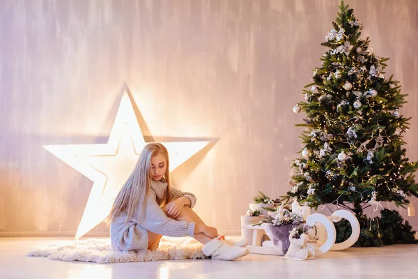 Όμορφη νεαρή γυναίκα, θέτοντας κάτω από το χριστουγεννιάτικο δέντρο σε ένα εσωτερικό διακοπές — Φωτογραφία Αρχείου