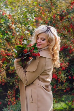 Sonbahar parkta sonraki karamuk Bush ayakta güzel zarif kadın