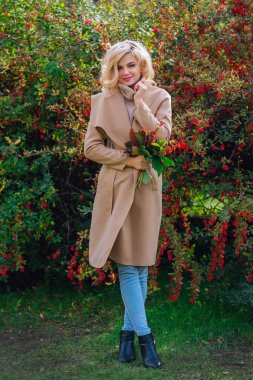 Sonbahar parkta sonraki karamuk Bush ayakta güzel zarif kadın