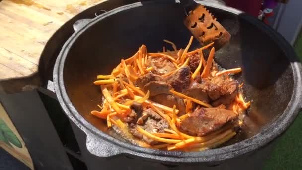 Cooking of pilaf outdoor. Chopped lamb frying in cauldron. — Stock Video