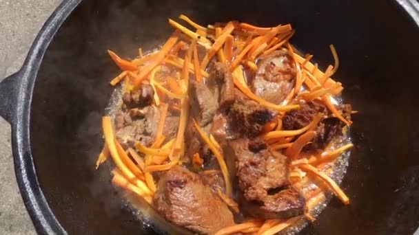 Cozinhar de pilaf ao ar livre. Fritamento de cordeiro picado em caldeirão . — Vídeo de Stock