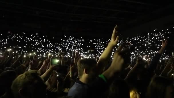 Novokuznetsk, Rússia - 04 de junho de 2019: Pessoas acenando com as mãos com smartphones com lanterna. Concerto de música ao vivo . — Vídeo de Stock