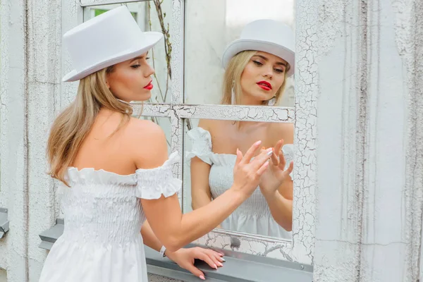 Сексуальная современная невеста в белой цилиндрической шляпе смотрит в зеркало — стоковое фото