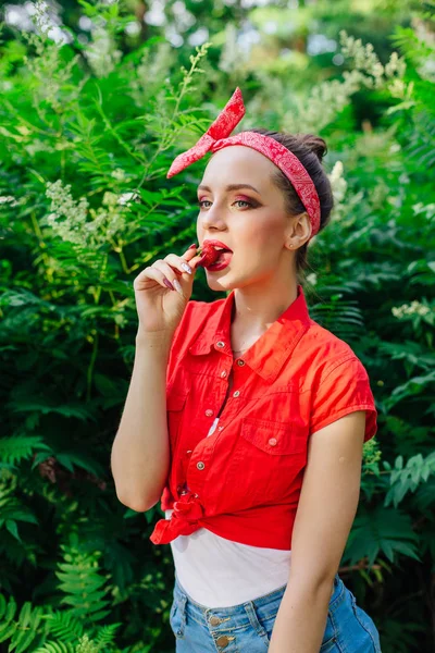 新鮮な自然なイチゴを食べる明るいメイクアップと美しい若いピンアップ女の子. — ストック写真
