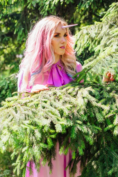 Fairy girl unicorn with pink hair in summer forest