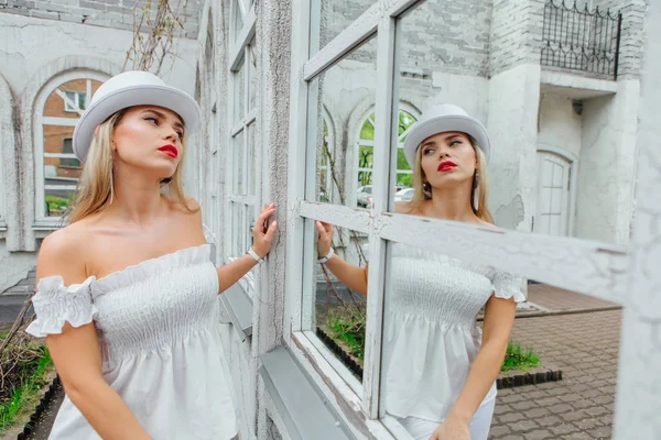 Sexy moderne Braut mit weißem Zylinderhut schaut ins Spiegelfenster — Stockfoto