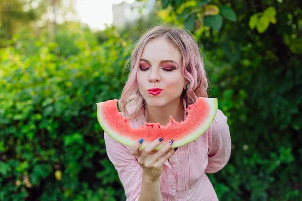 Beautiful young woman with pink hair enjoying watermelon — Stock Photo, Image