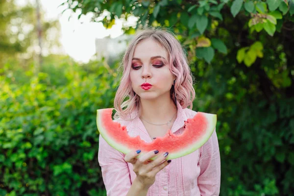 Mooie jonge vrouw met roze haren genieten van watermeloen — Stockfoto