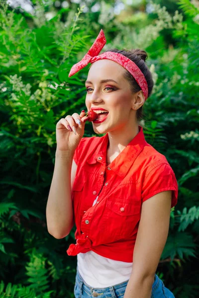 Hermosa joven pin up chica con brillante maquillaje comer fresa natural fresca . — Foto de Stock