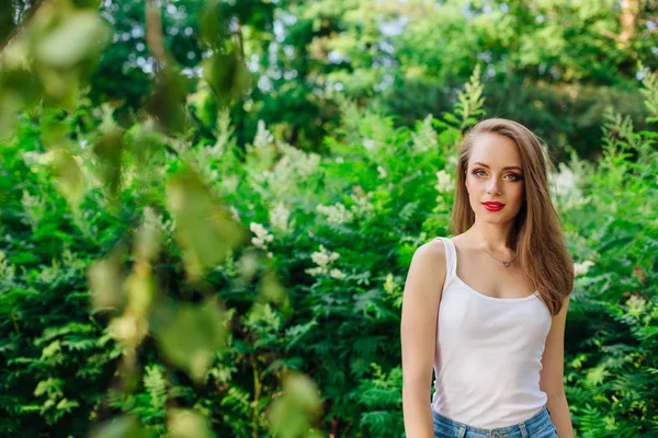 Ung kvinna klädd i vit skjorta i sommarpark — Stockfoto