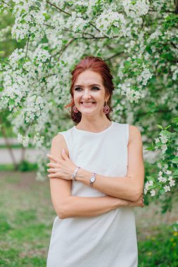 Elma ağacının altında güzel beyaz elbise giyen büyüleyici kadın