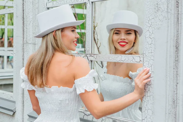 Sexy novia moderna en sombrero de cilindro blanco mirando en la ventana del espejo — Foto de Stock