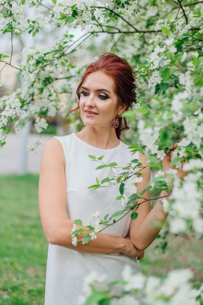 Charmante vrouw het dragen van mooie witte jurk onder de appelboom — Stockfoto