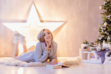 Döşeme ve bir tatil iç Noel ağacı altında kitap okuma güzel genç kadın