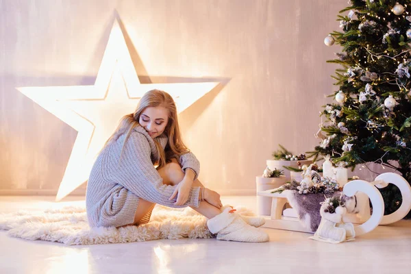 Schöne junge Frau posiert unter dem Weihnachtsbaum in einem Urlaub Interieur — Stockfoto
