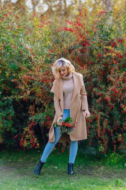 Sonbahar parkta sonraki karamuk Bush ayakta güzel zarif kadın
