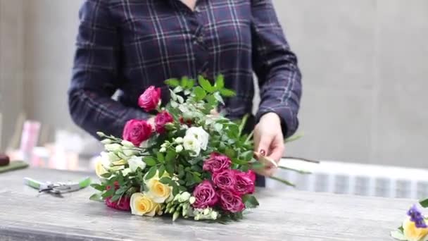 Kvinnlig florist arrangerar blommor i blomsteraffär. Kvinna bundenhet en bukett — Stockvideo