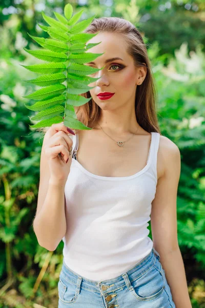 Портрет женщины с красивыми зелеными глазами, одетой в белую рубашку с листком рядом с одним глазом . — стоковое фото