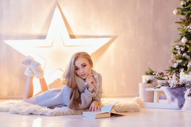 Döşeme ve bir tatil iç Noel ağacı altında kitap okuma güzel genç kadın