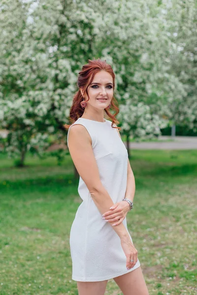 Mujer encantadora vistiendo hermoso vestido blanco bajo el manzano — Foto de Stock