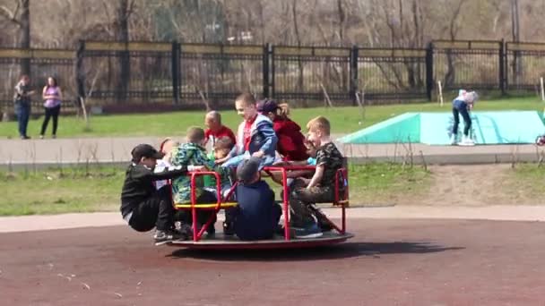 Novokuznetsk, Russa - 05 de maio de 2019: Crianças ativas brincando no playground, correndo com um carrossel no parque — Vídeo de Stock