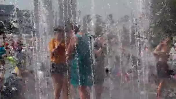 俄罗斯克麦罗沃州诺沃库兹涅茨克 - 2019年6月28日：快乐的青少年在城市喷泉的水中嬉戏，在炎热的一天享受清凉的水流. — 图库视频影像