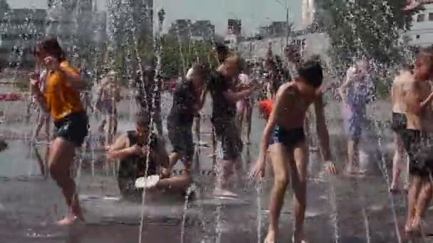 Novokuznetsk, Region Kemerowo, Russland - 28. Juni 2019: fröhliche Teenager planschen im Wasser eines Stadtbrunnens und genießen die kühlen Wasserströme an einem heißen Tag. — Stockvideo